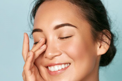 Bright and glowing skin with a person applying moisturizer on their face, surrounded by dry, windy harmattan conditions. The image represents skincare tips for maintaining hydration and protection during the harmattan season.